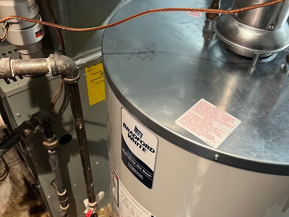 Tank-style water heater installation and connection work.