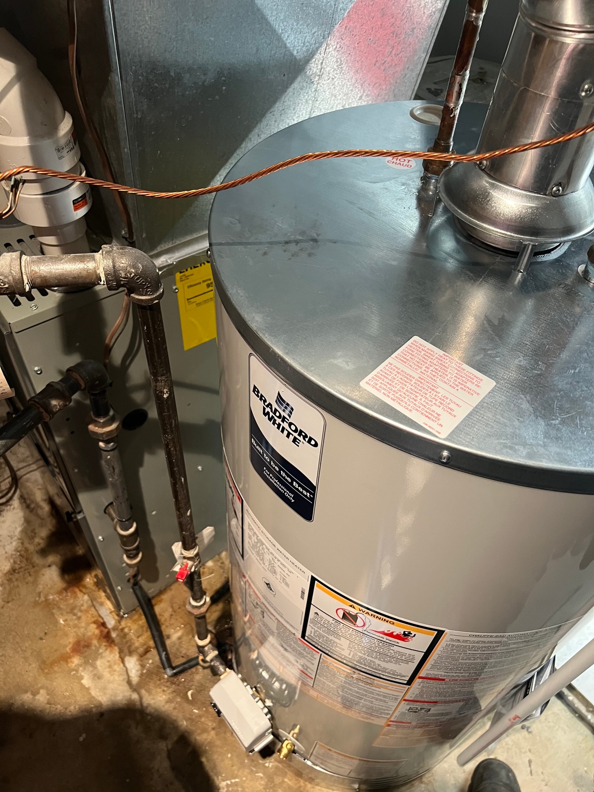 Tank-style water heater installation and connection work.